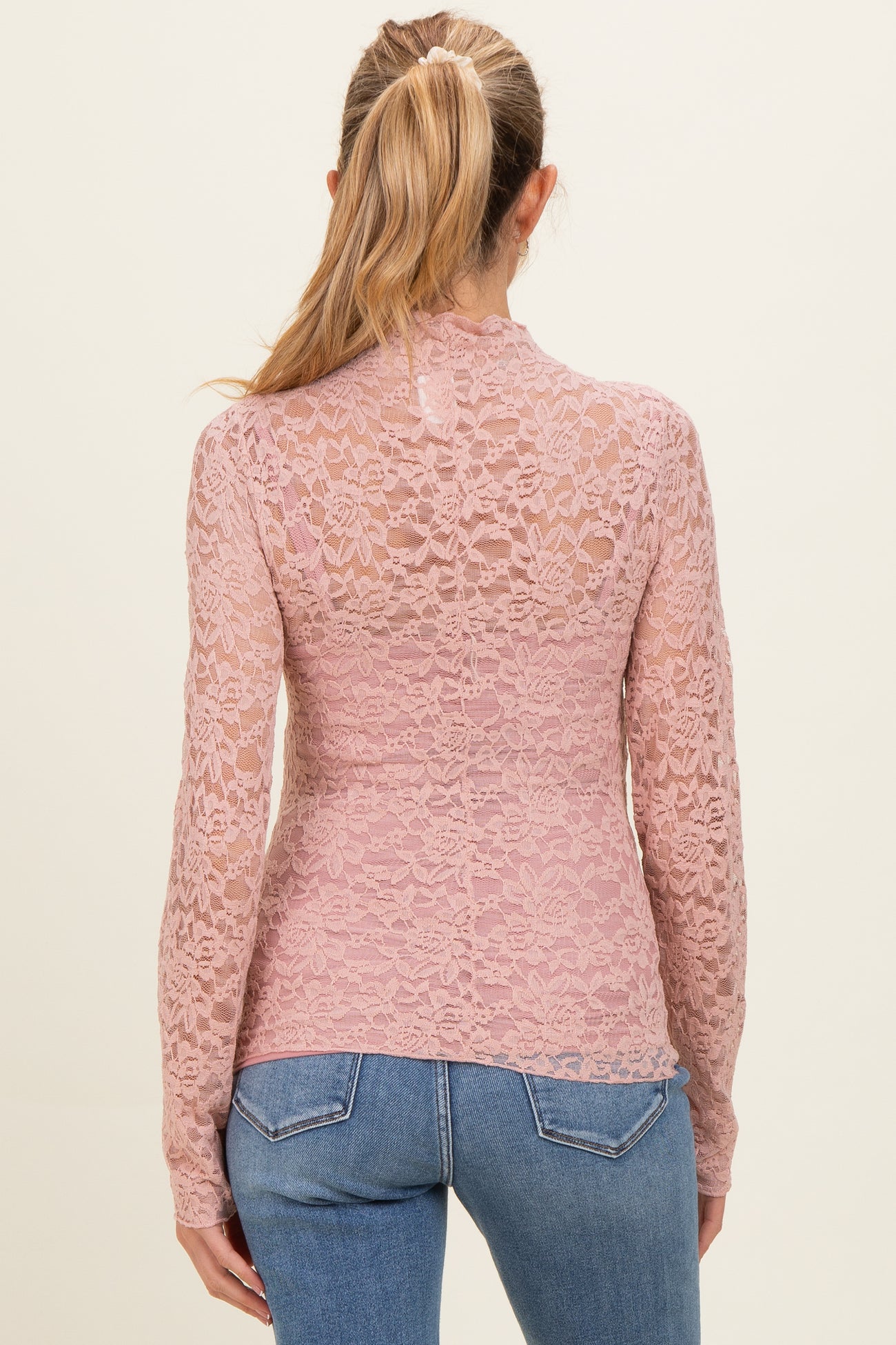 woman wearing a dusty pink lace maternity top with long sleeves and sheer back detail