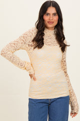 woman wearing a light yellow long sleeve lace top with a mock neck and fitted style, paired with blue jeans