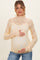 woman wearing a light yellow lace maternity top and holding her baby bump