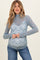 woman wearing a light blue maternity lace top with a mock neck and long sleeves, showing her baby bump