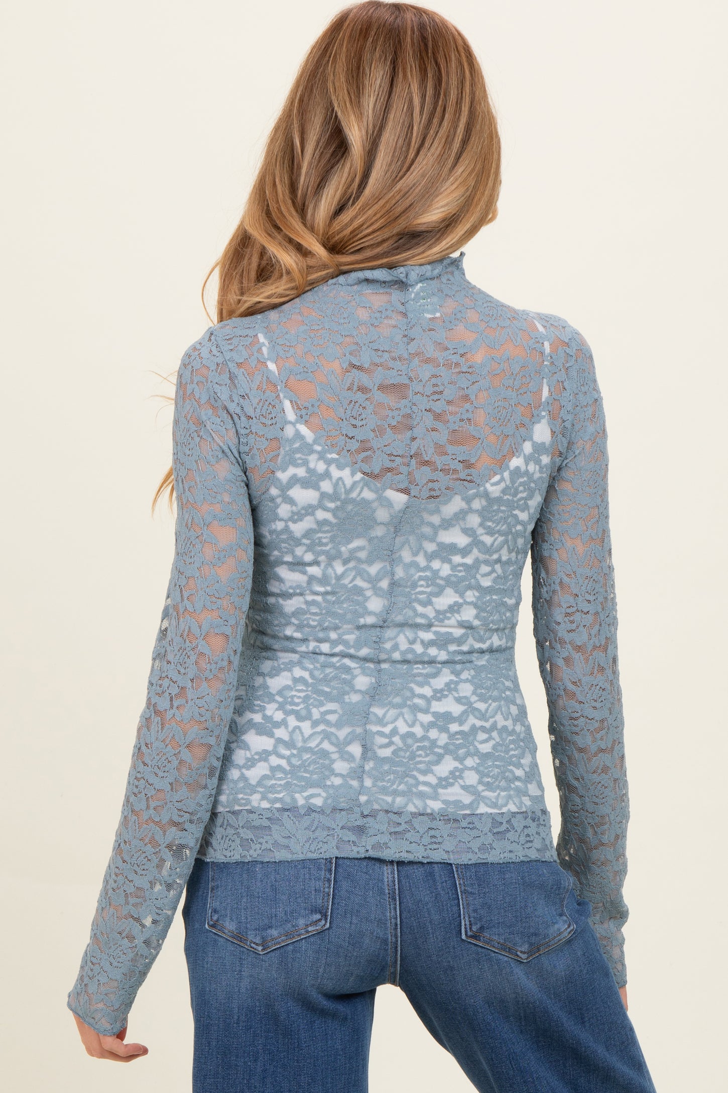 woman wearing a light blue lace maternity top with a high collar, showing a fitted style and back detail