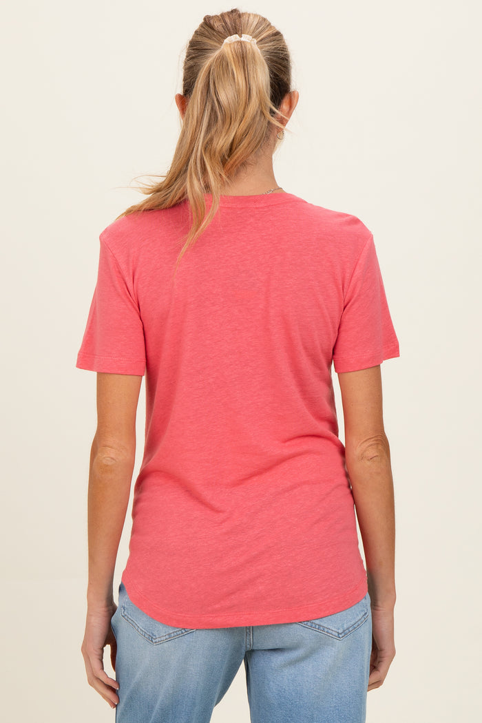 woman wearing a coral short sleeve maternity top, seen from the back with light blue jeans