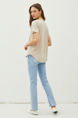 woman wearing a beige t-shirt and light blue straight leg jeans, facing away from the camera
