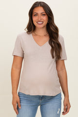 woman wearing a light beige maternity top with a v-neckline and short sleeves, showing her baby bump