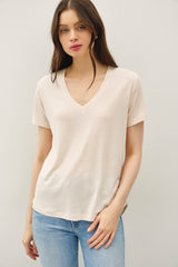 woman wearing a light beige short sleeve v-neck t-shirt paired with blue jeans