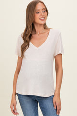 woman wearing a light pink v-neck maternity top with short sleeves and a baby bump visible