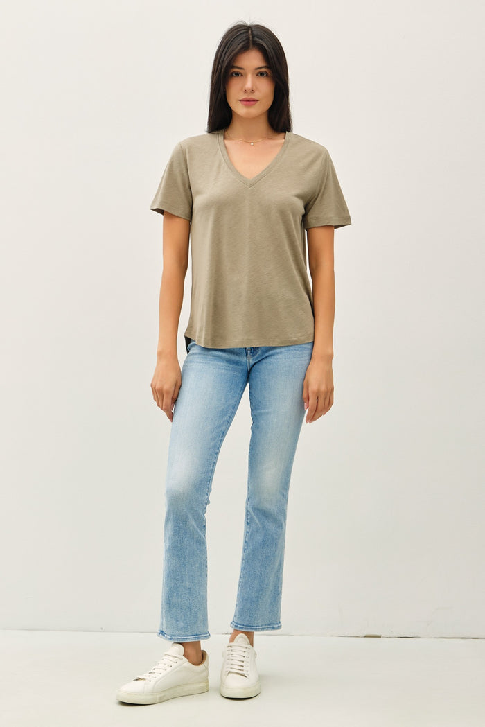 woman wearing a taupe v-neck t-shirt with short sleeves and light blue flared jeans