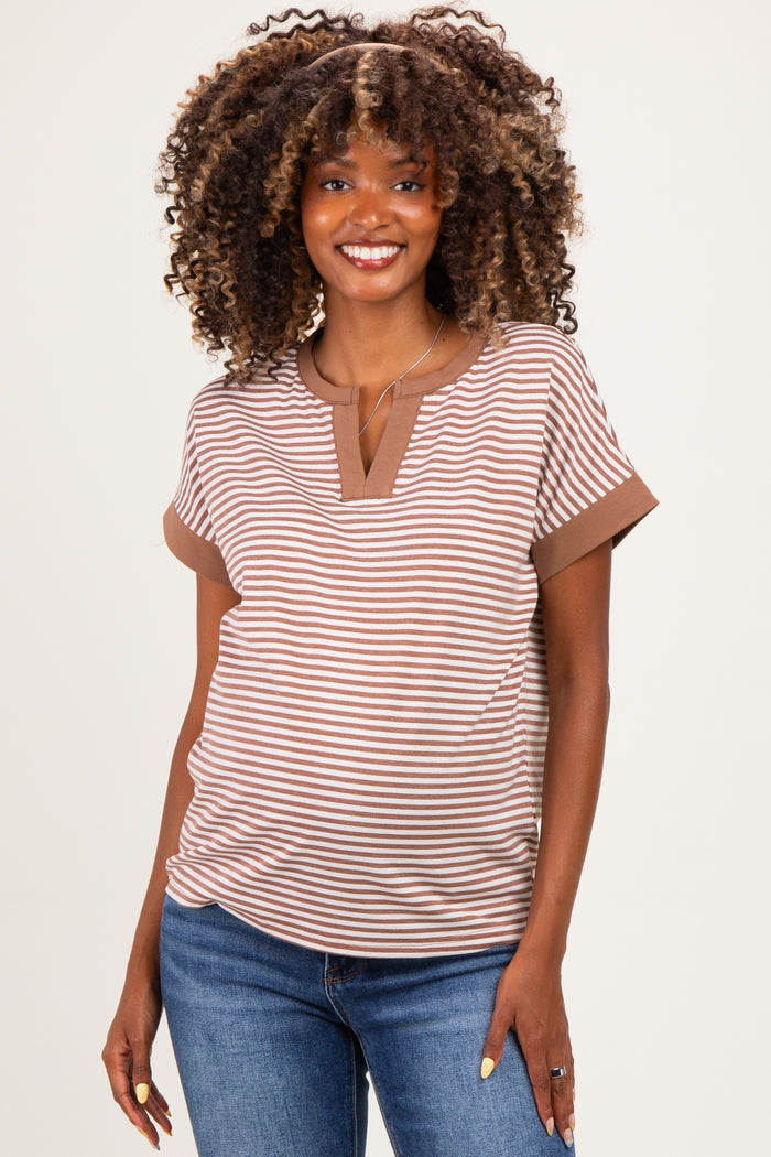 woman wearing a brown and beige striped maternity top with a slight v-neck and short sleeves, smiling at the camera