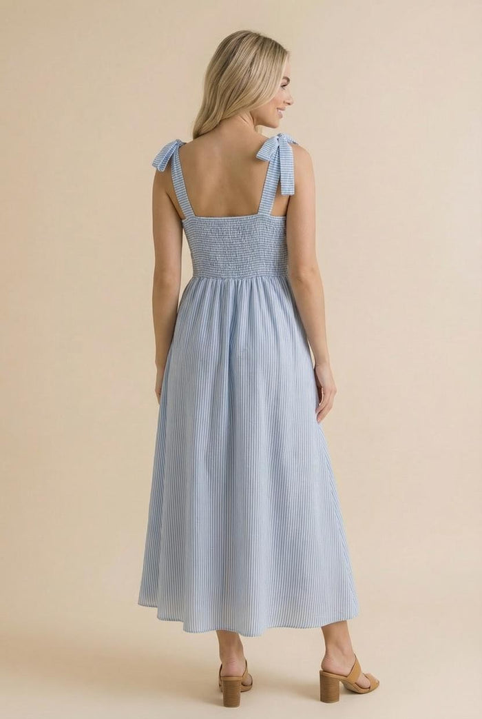 woman wearing a blue and white striped maxi dress with shoulder ties and smocked bodice, shown from the back