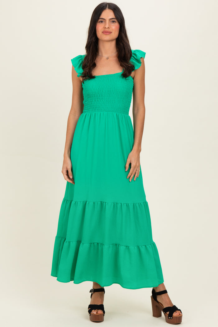 woman wearing a bright green smocked maxi dress with ruffle sleeves and tiered skirt, standing confidently