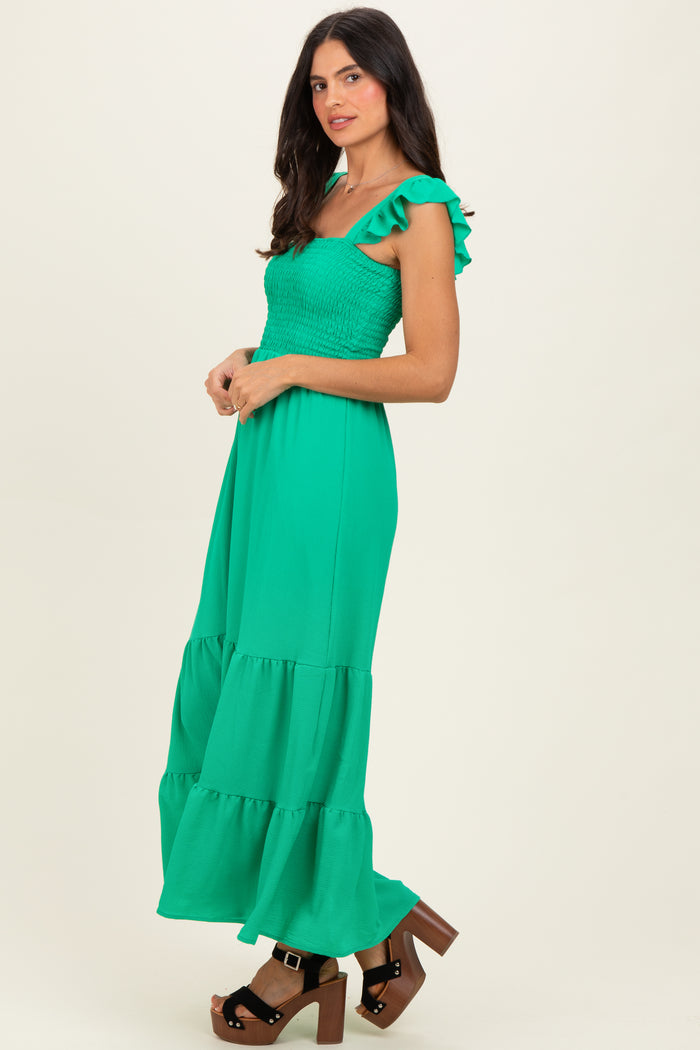 woman wearing a green off-the-shoulder maxi dress with ruffled sleeves and a tiered skirt