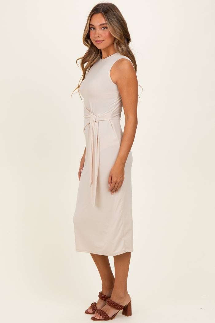 woman wearing a fitted beige midi dress with a tied waist detail and a scoop neckline