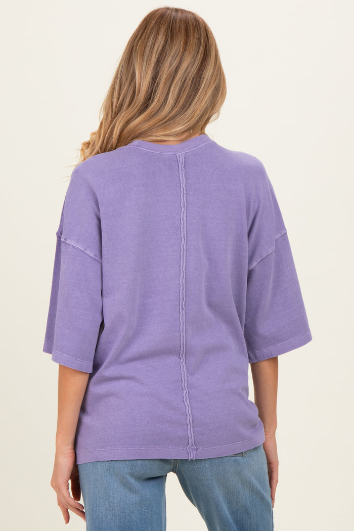 woman wearing a purple oversized maternity top, showing a relaxed fit and back seam detail