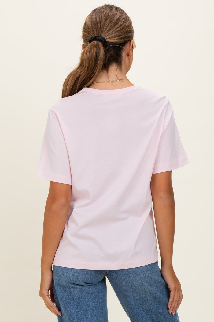 woman wearing a light pink short sleeve t-shirt with a relaxed fit