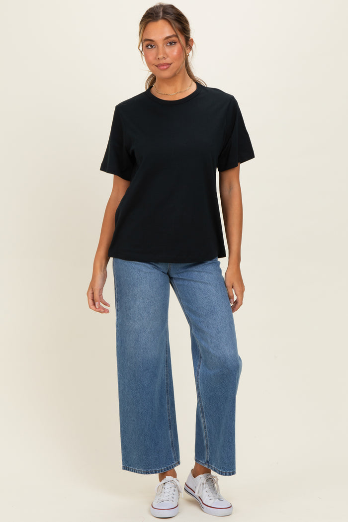 woman wearing a black oversized t-shirt with short sleeves and high-waisted wide-leg jeans, paired with white sneakers