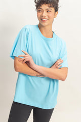 woman wearing a light blue short sleeve t-shirt and black leggings, smiling with arms crossed