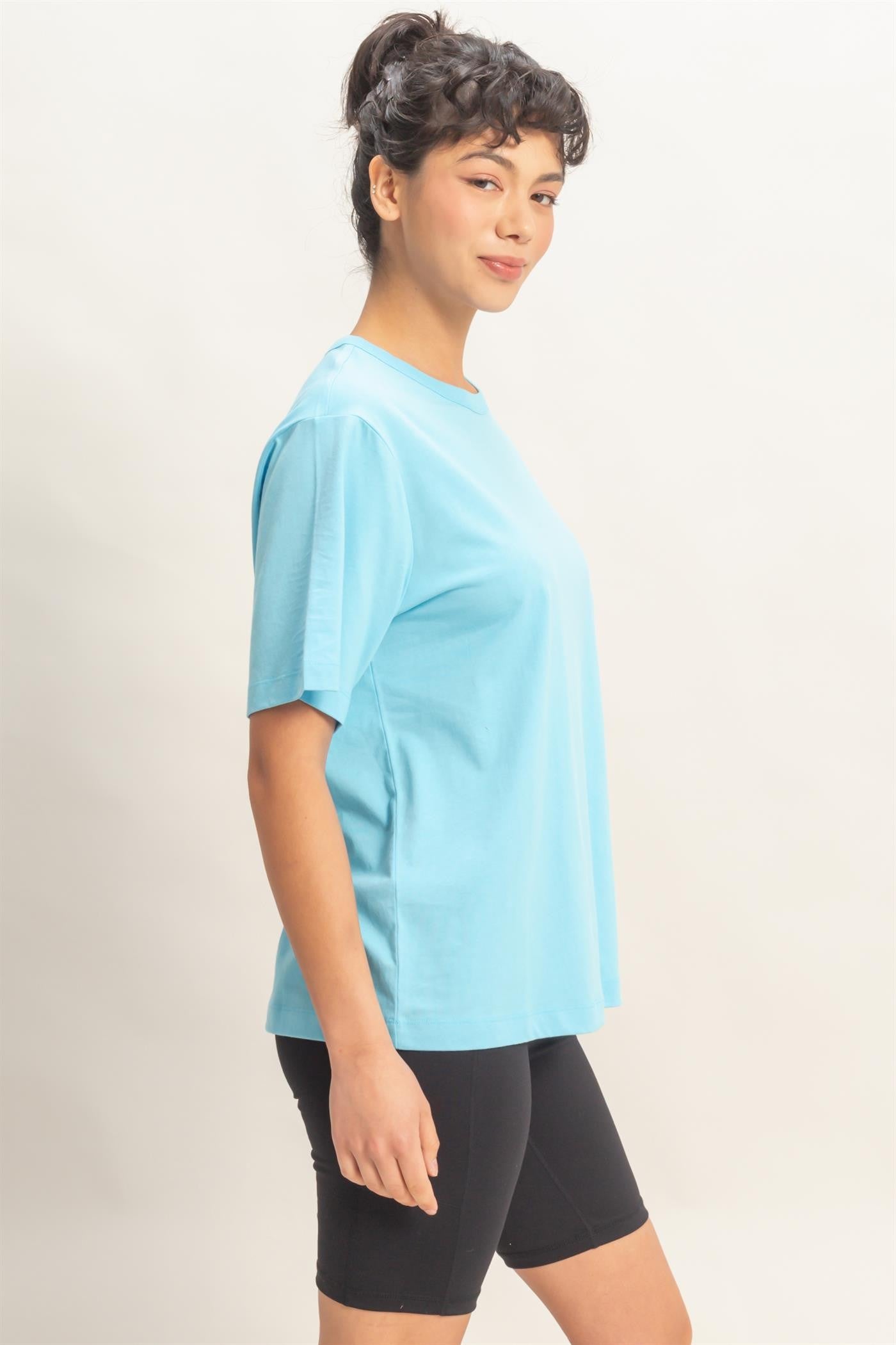 woman wearing a light blue short sleeve t-shirt and black cycling shorts, standing sideways with a smile