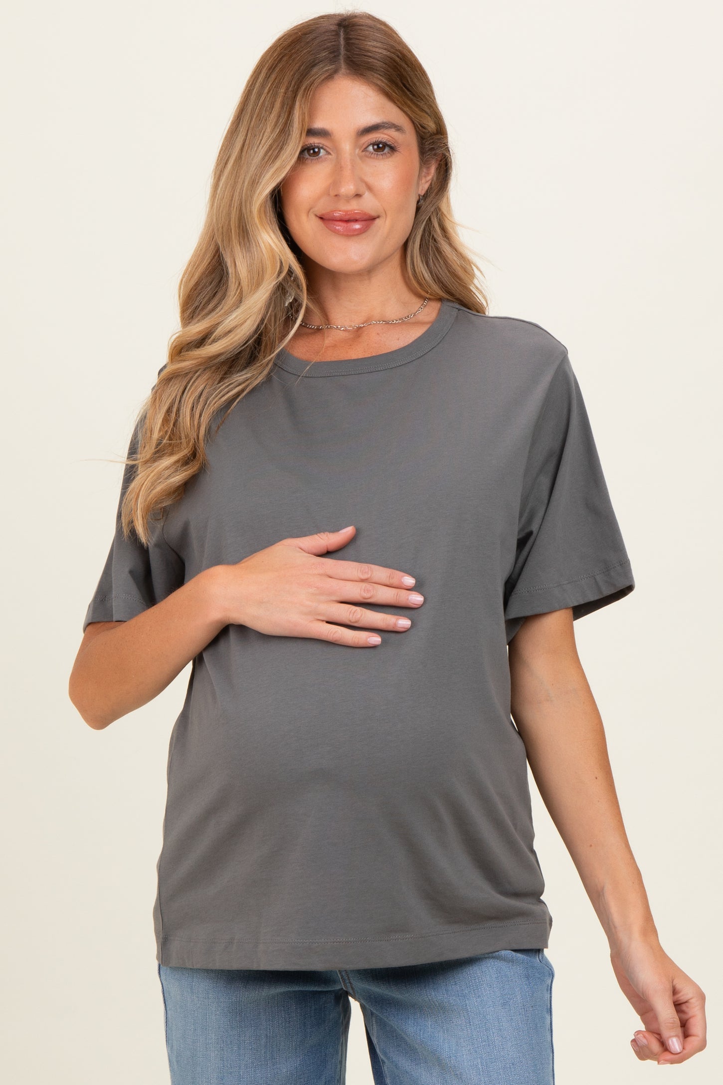 woman wearing a gray maternity short sleeve top and holding her baby bump