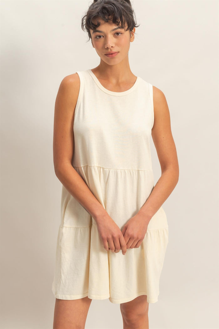 woman wearing a cream sleeveless tiered dress with a relaxed fit