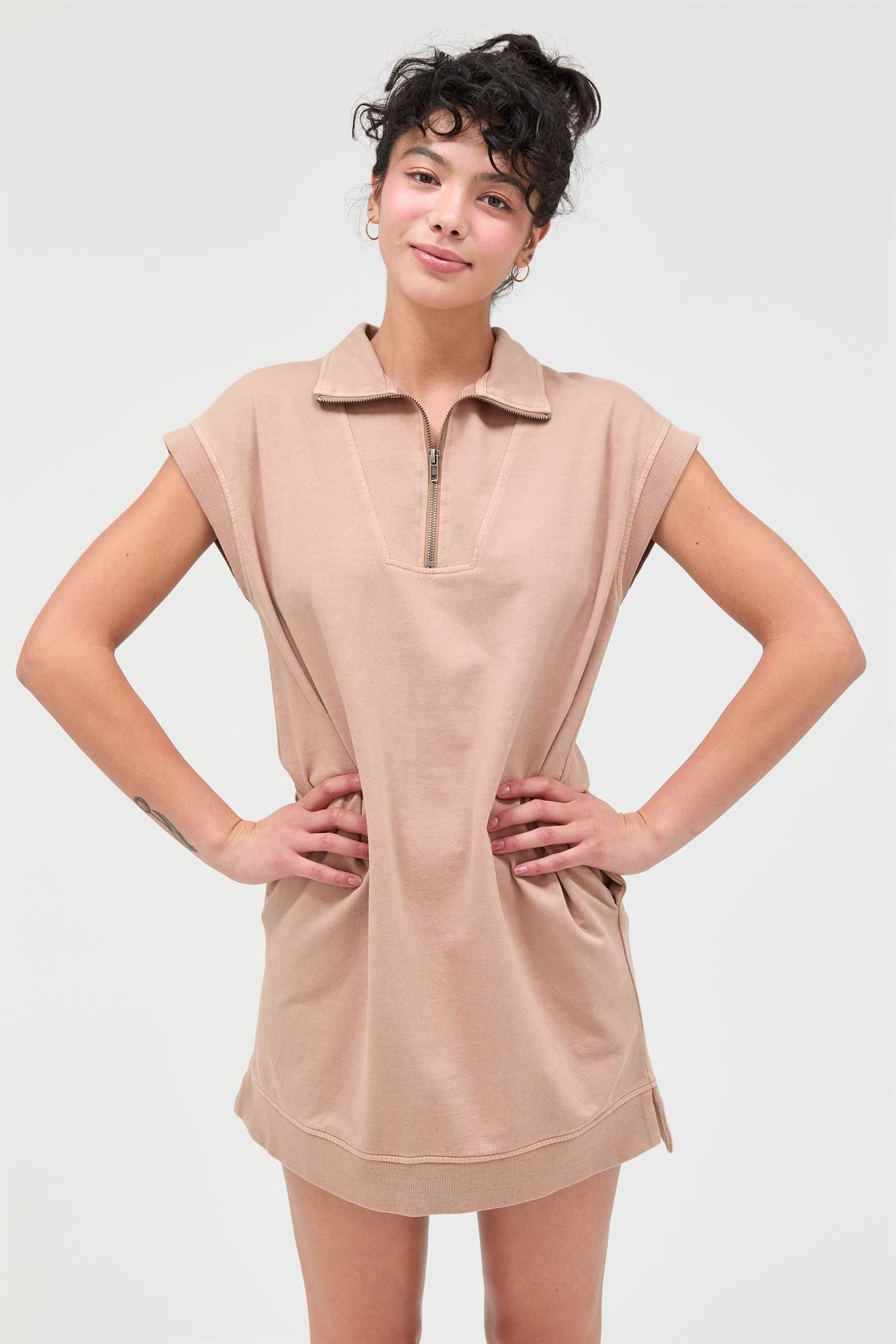 woman wearing a beige short sleeve zip-up dress with a polo collar and relaxed fit