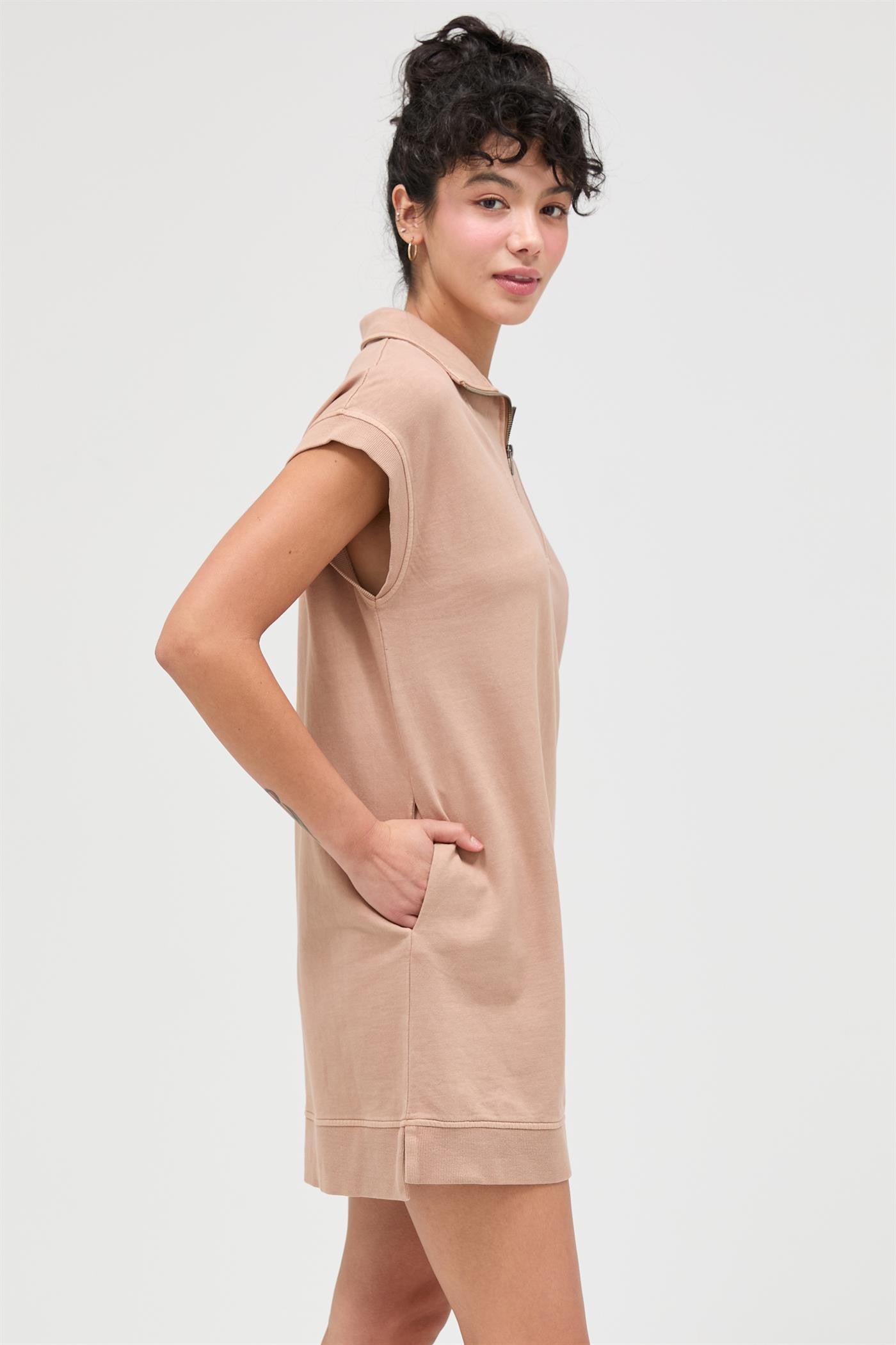 woman wearing a light brown short sleeve polo dress with side pockets and a relaxed fit