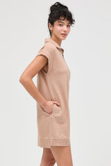 woman wearing a light brown short sleeve polo dress with side pockets and a relaxed fit