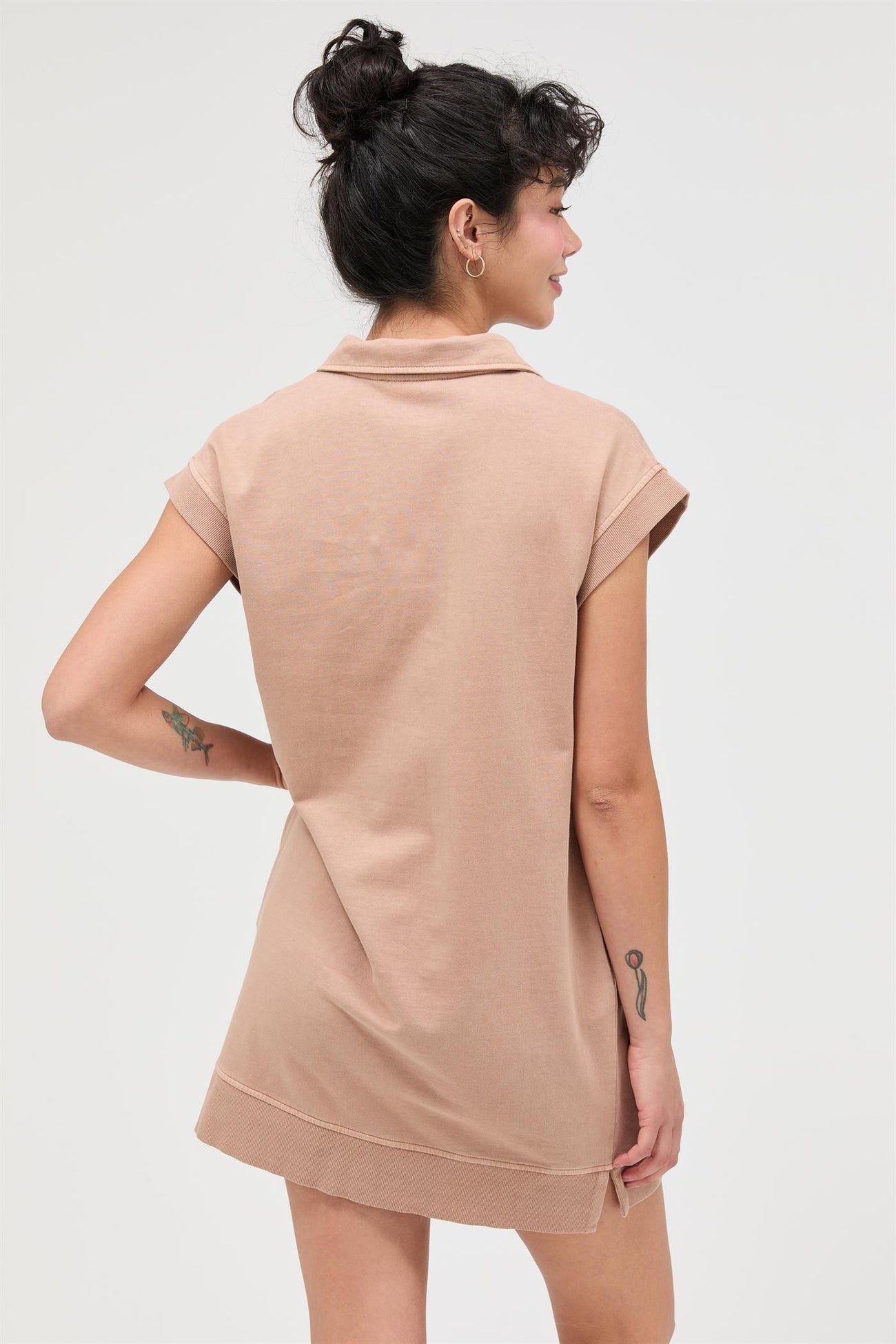 woman wearing a beige short-sleeve polo dress with a relaxed fit and a stylish collar, seen from the back