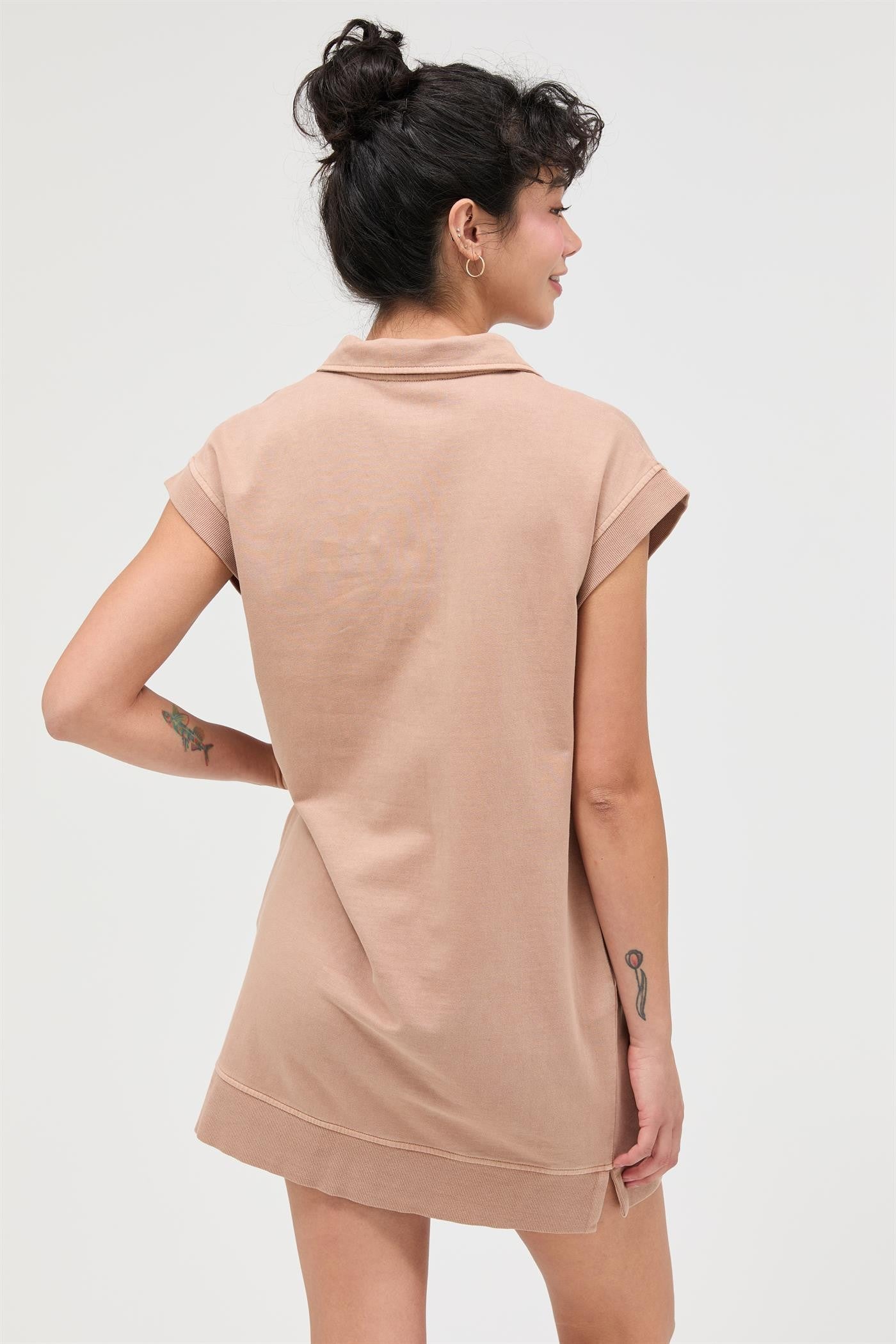 woman wearing a beige short-sleeve polo dress with a relaxed fit and a stylish collar, seen from the back