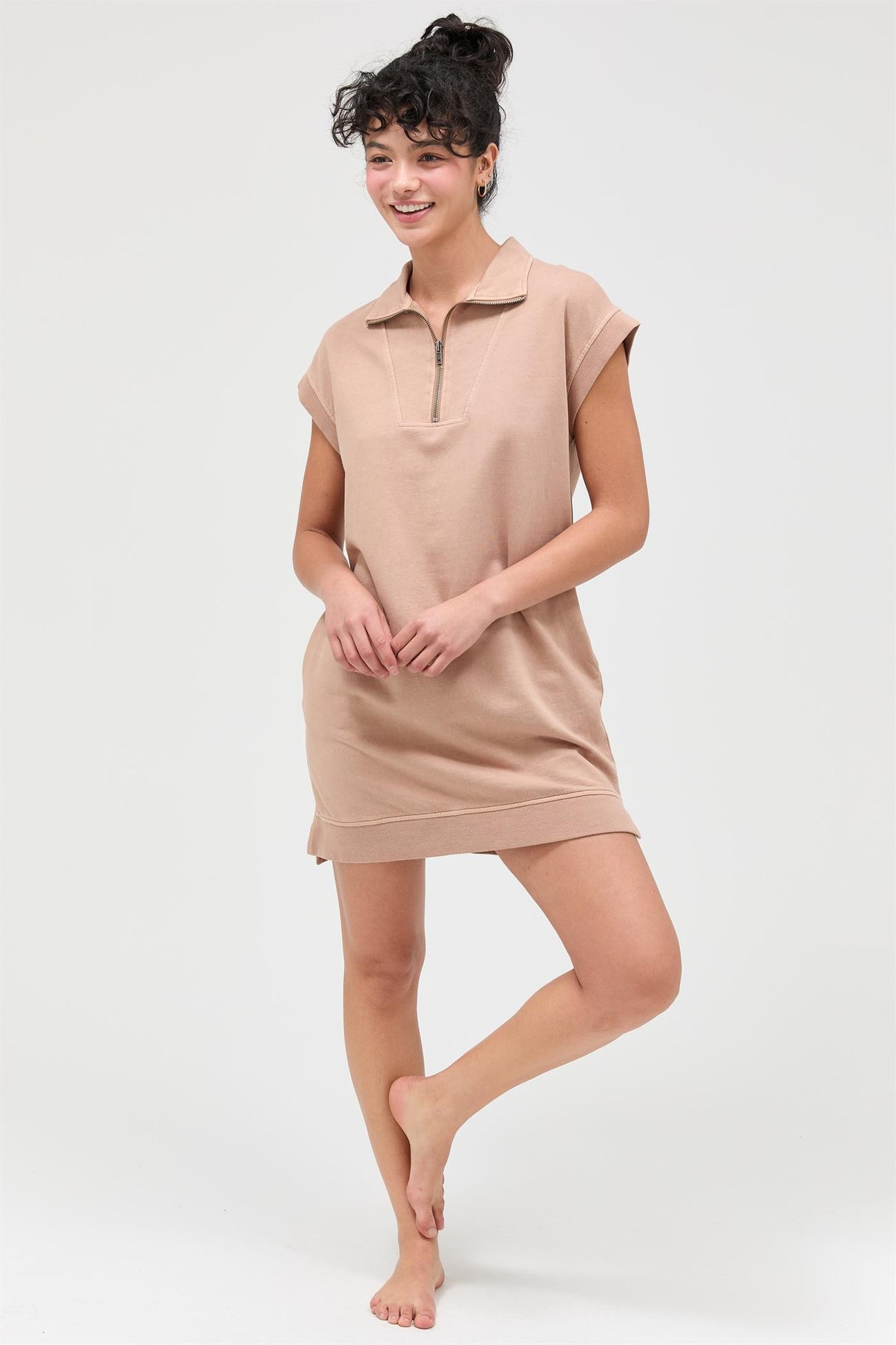 woman wearing a beige short sleeve polo dress with a zippered collar and a relaxed fit