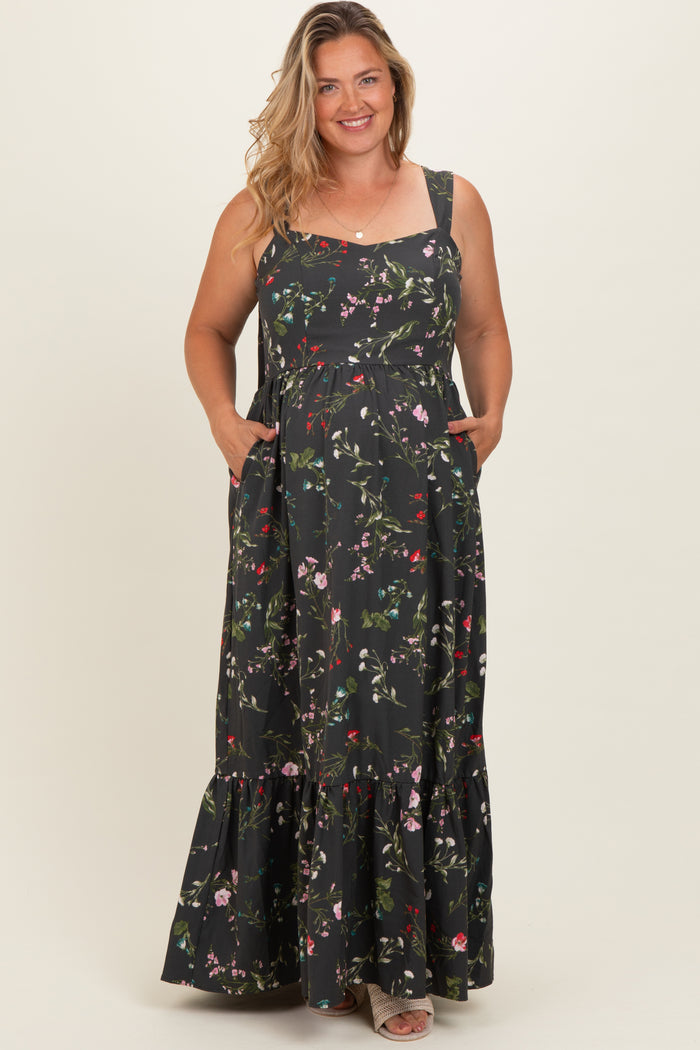 woman wearing a black floral maternity maxi dress with pockets and a tiered skirt