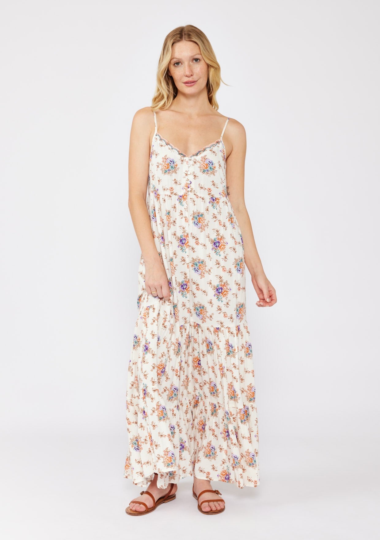 woman wearing a cream floral maxi dress with spaghetti straps and a tiered skirt