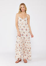 woman wearing a cream floral maxi dress with spaghetti straps and a tiered skirt