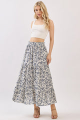 woman wearing a white crop top and a long floral maxi skirt with blue patterns