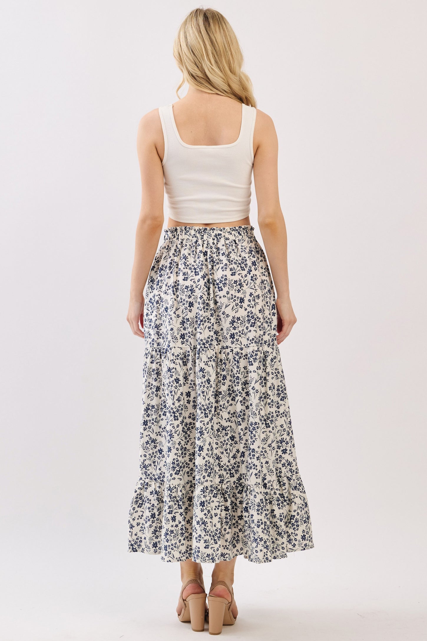 woman wearing a white floral maxi skirt and a fitted white crop top, viewed from the back