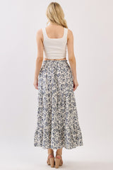 woman wearing a white floral maxi skirt and a fitted white crop top, viewed from the back