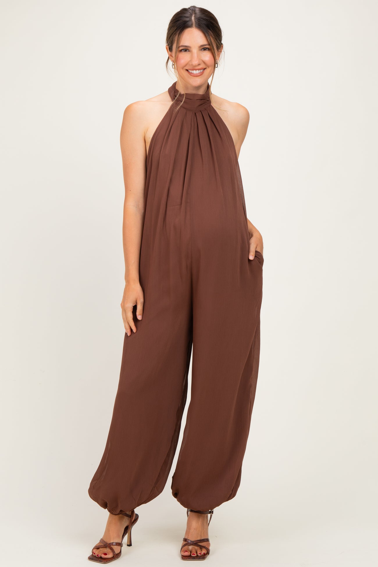 woman wearing a brown halter neck maternity jumpsuit with a baby bump and loose, flowing pants