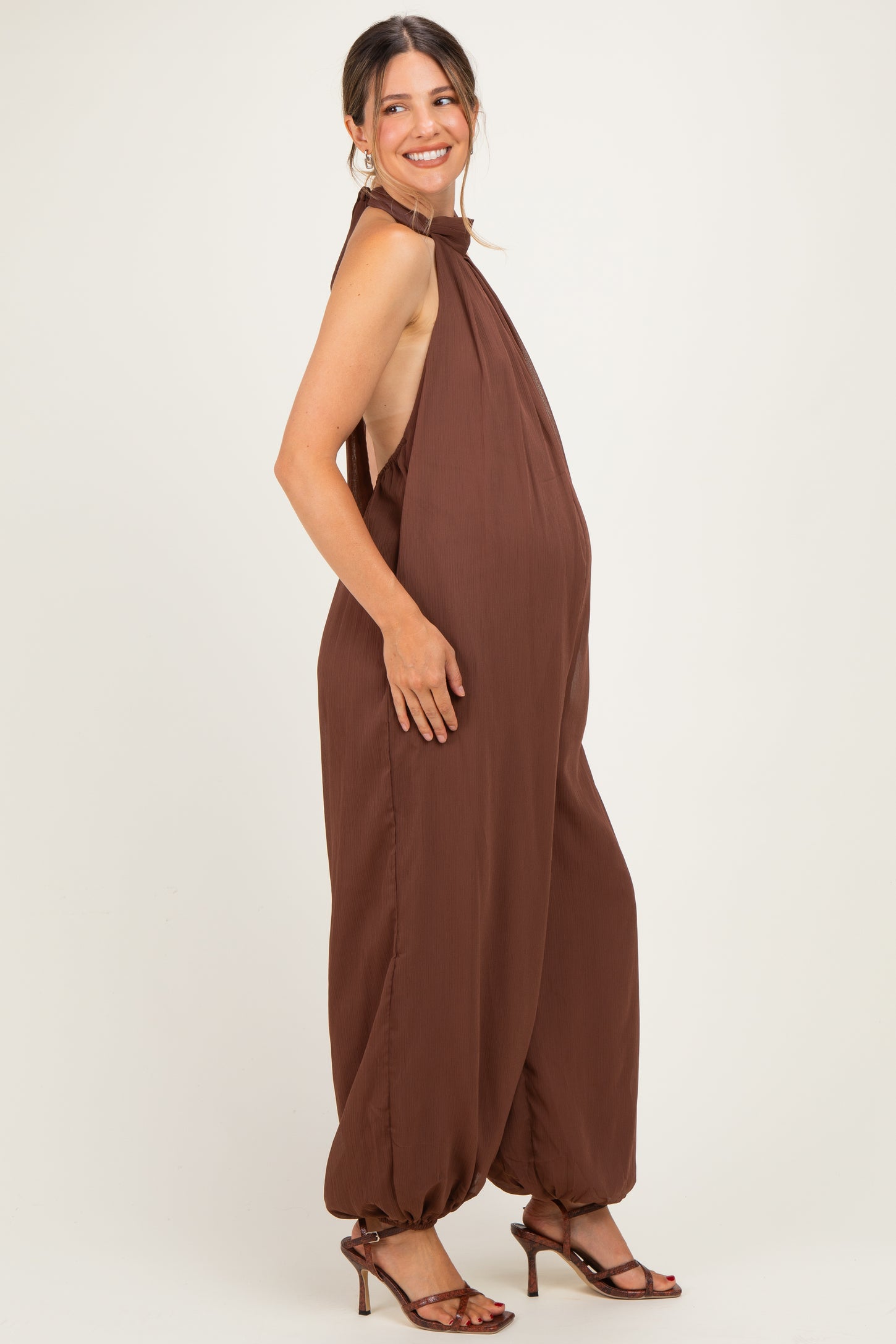 woman wearing a brown maternity jumpsuit with a halter neck and a visible baby bump