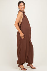 woman wearing a brown maternity jumpsuit with a halter neck and a visible baby bump