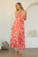 woman wearing a red and white patterned maxi dress with a halter neck and a flowing skirt
