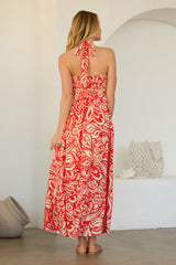 woman wearing a red and white floral maxi dress with a halter neck and an open back