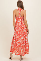 woman wearing a red floral maternity maxi dress with a halter neck and smocked back detail