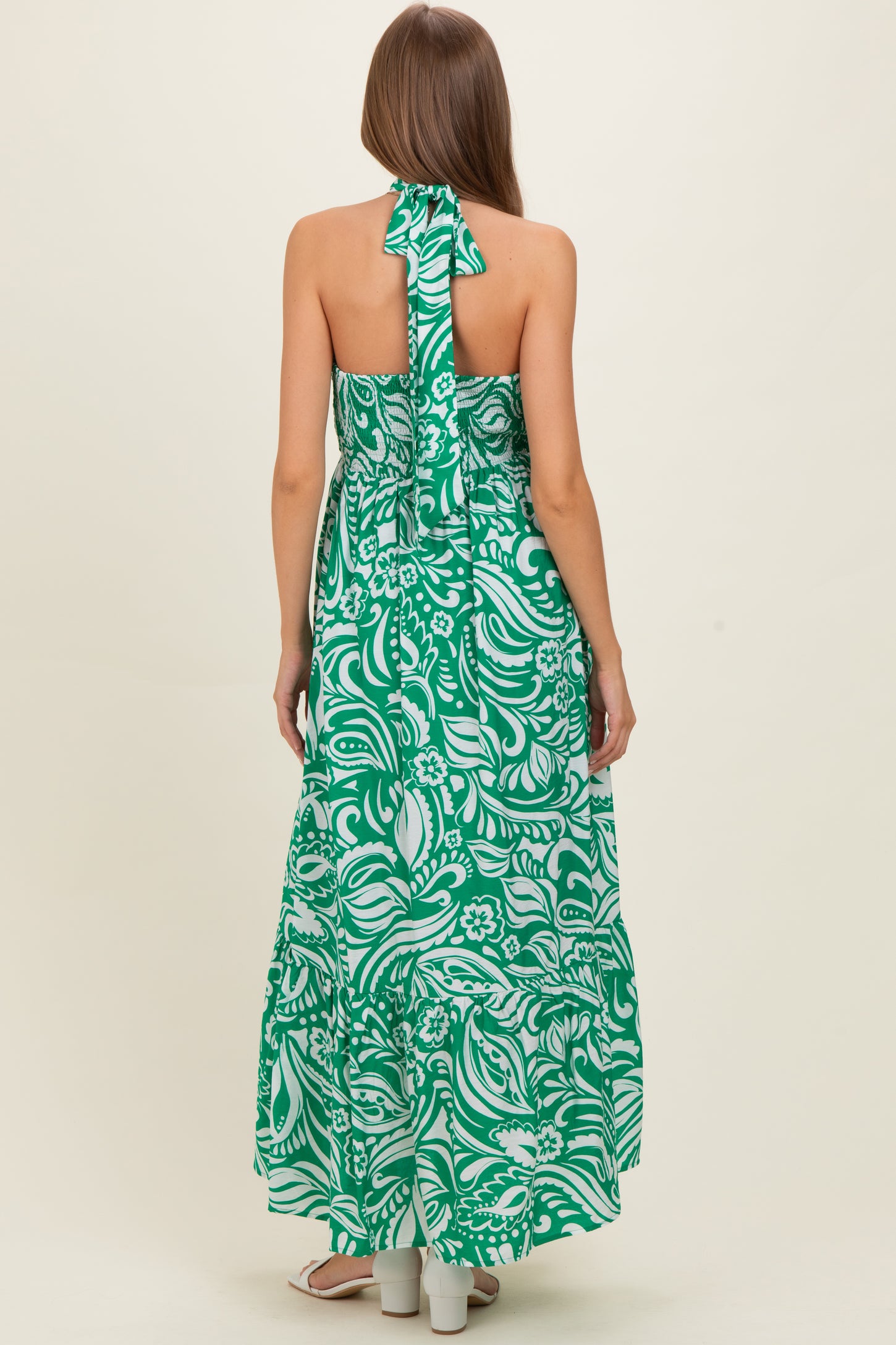 woman wearing a green floral maternity maxi dress with a halter neck and open back