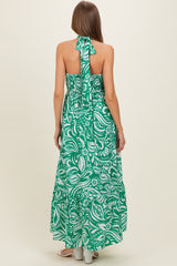 woman wearing a green floral maternity maxi dress with a halter neck and open back