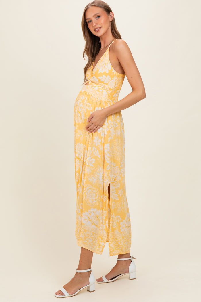 woman wearing a yellow floral maternity maxi dress and holding her baby bump