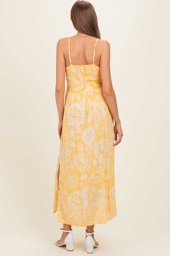 woman wearing a yellow floral maternity maxi dress with spaghetti straps and side slits