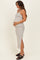 woman wearing a cream and black striped maternity dress with a side slit and holding her baby bump