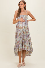 woman wearing a floral print maternity maxi dress, gently cradling her baby bump