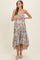 woman wearing a floral print maternity maxi dress, gently cradling her baby bump