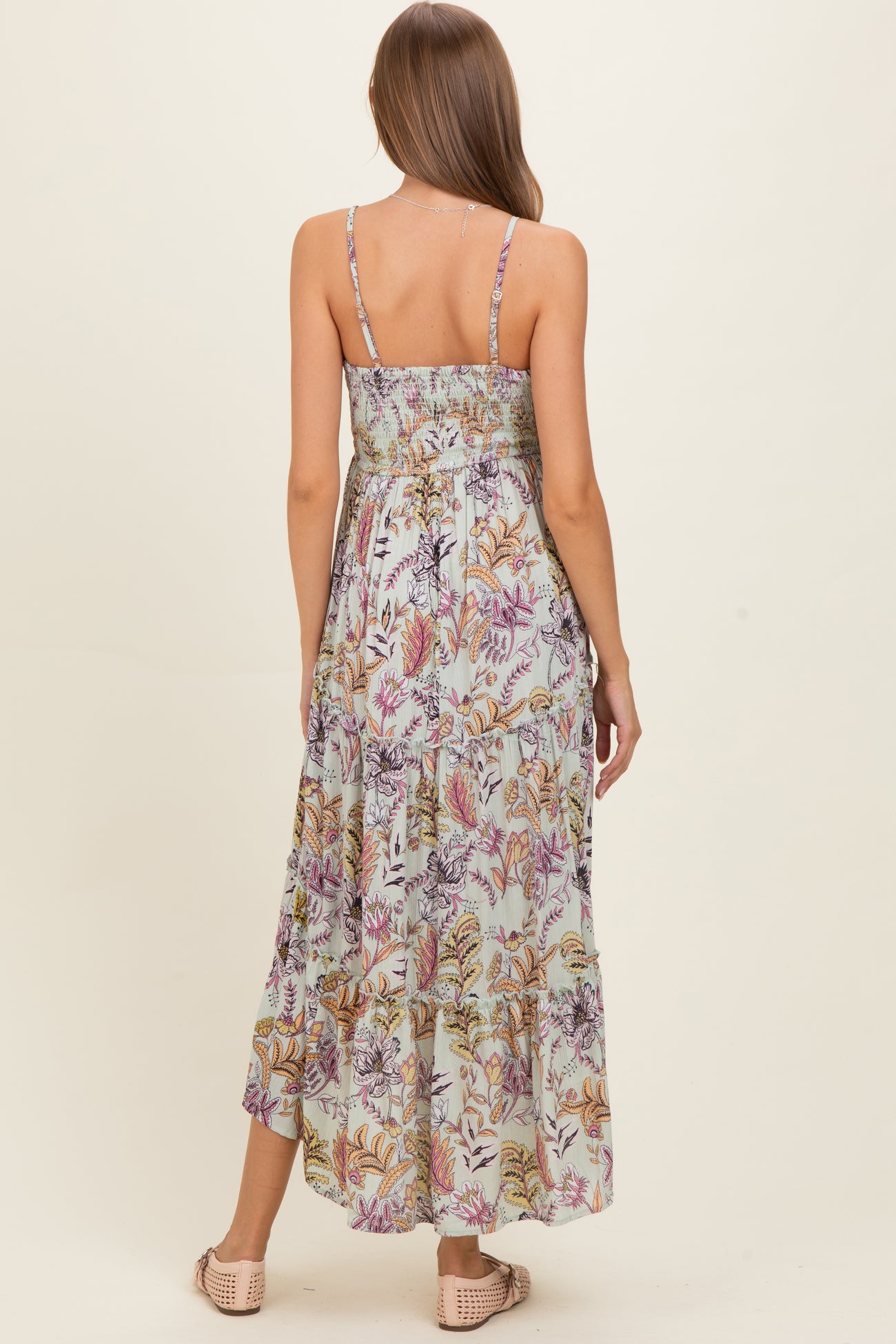 woman wearing a floral print maternity maxi dress with a smocked bodice and adjustable straps, showing the back view