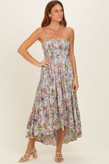 woman wearing a floral maxi dress with spaghetti straps and a tiered hemline, standing in a light stance